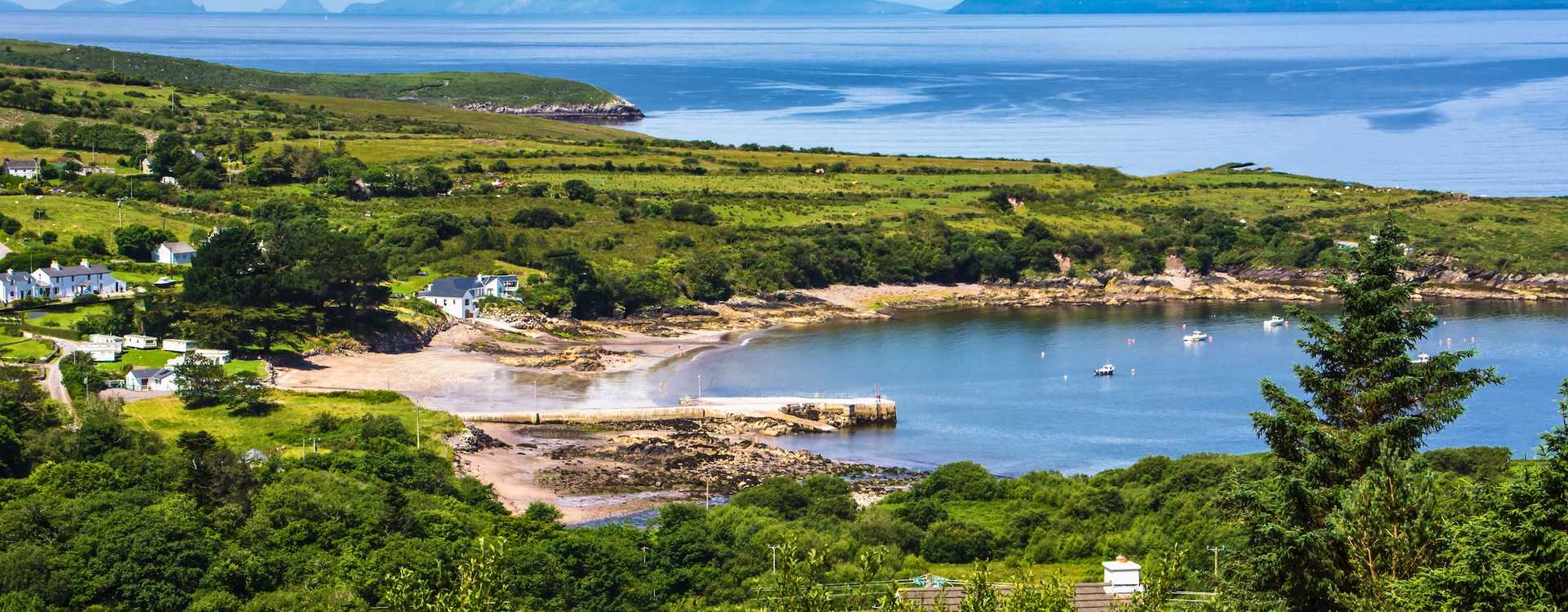 Ring of Kerry natural landscapes – Book the best local guided loops and round-trip bus excursions from Killarney, Cork, or Dublin in 2026 Scenic view of small colorful boats moored on a tranquil lake surrounded by the lush green forests and rolling peaks of County Kerry – Definitive travel guide for Ring of Kerry excursions in 2026
